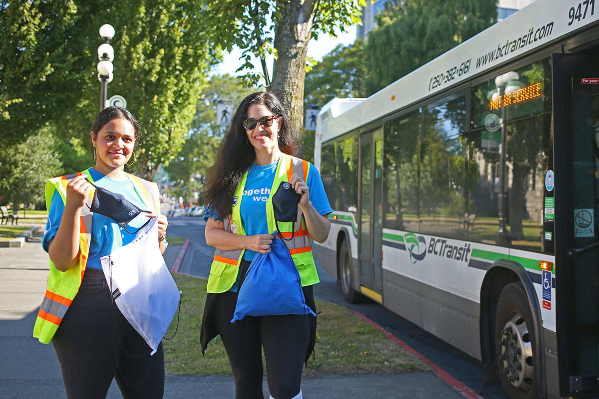 Alaaliyah Jariwala, left and Sarah Phillips hand out masks at a bus stop outside of the legislature building in Victoria Monday. BC transit launched a province-wide campaign that encourages transit users to wear a mask. (Dawn Gibson/News Staff)