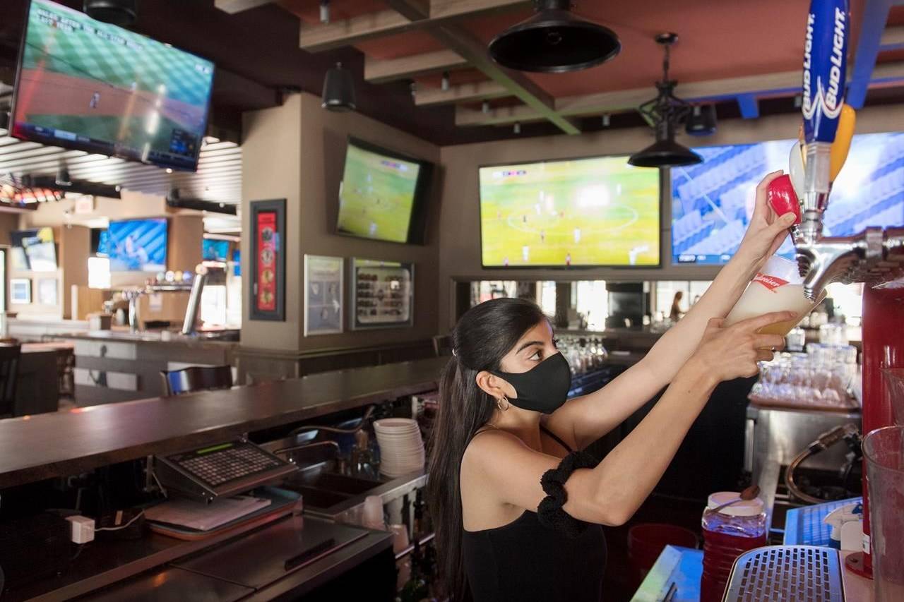A server pulls a pint of beer at Station Sports bar in Montreal, Saturday, July 25, 2020, as the COVID-19 pandemic continues in Canada and around the world. THE CANADIAN PRESS/Graham Hughes