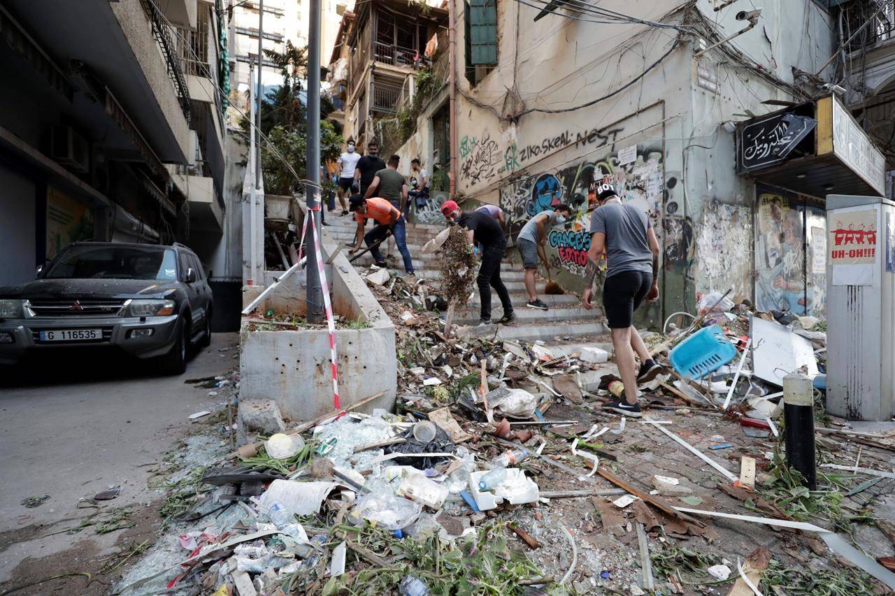 People clean up after a massive explosion in Beirut, Lebanon, Wednesday, Aug. 5, 2020. Massive explosions rocked downtown Beirut on Tuesday, flattening much of the port, damaging buildings and blowing out windows and doors as a giant mushroom cloud rose above the capital. Witnesses saw many people injured by flying glass and debris. (AP Photo/Hassan Ammar)