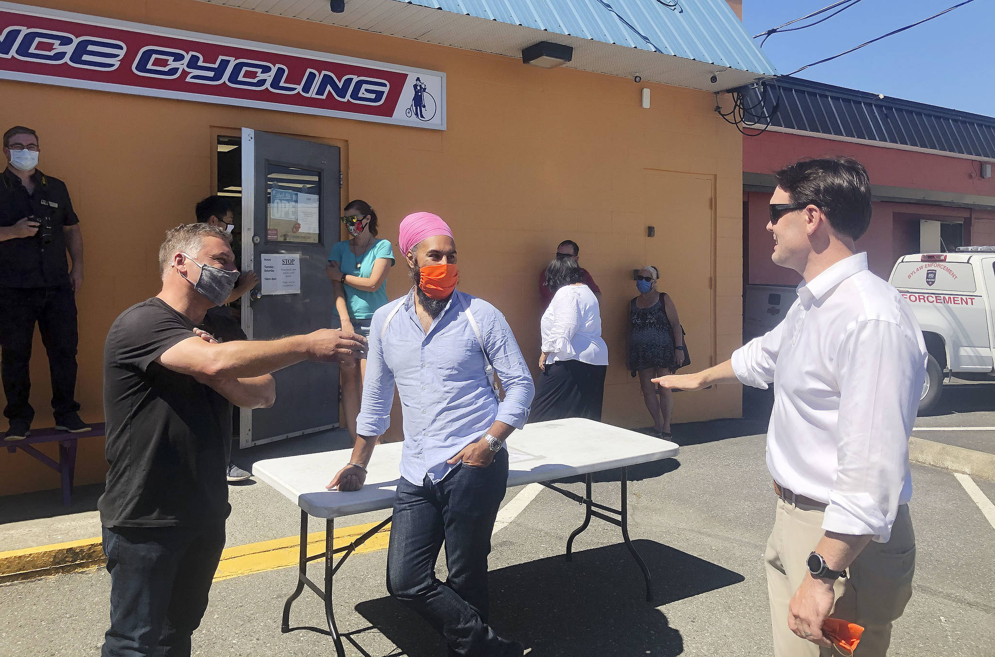 Experience Cycling owner Will Arnold, left, and MP Alistair MacGregor, right, talk about the Cowichan Valley’s homelessness and addiction problems with federal NDP leader Jagmeet Singh on Saturday, Aug. 15. (Kevin Rothbauer/Citizen)