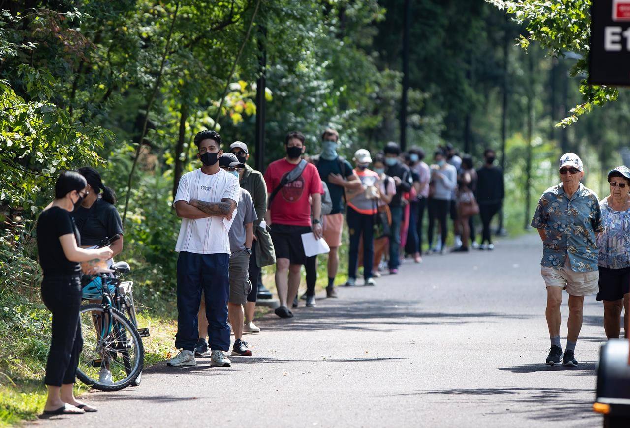 People wait in line at a COVID-19 testing facility in Burnaby, B.C., on Thursday, August 13, 2020. A new public opinion study suggests Canadians believe the COVID-19 crisis has brought their country together, while Americans blame the pandemic for worsening their cultural and political divide. THE CANADIAN PRESS/Darryl Dyck