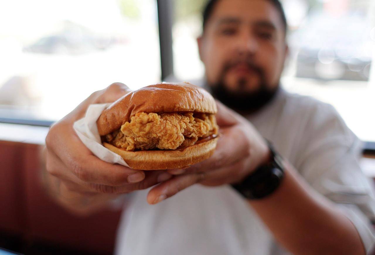 Randy Estrada holds up his chicken sandwiches at a Popeye’s in Kyle, Texas, Thursday, Aug. 22, 2019. The much-hyped chicken sandwich will go on sale Canada-wide on Monday, after trial launches in Edmonton and southern Ontario earlier this year. THE CANADIAN PRESS/AP-Eric Gay