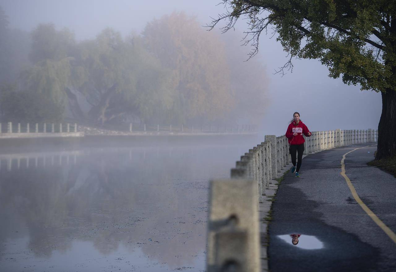 A runner makes their way along a pathway as fog blankets the Rideau Canal in Ottawa, on Wednesday, Oct. 14, 2020. New fitness guidelines urge adults to limit screen time and sedentary behaviour while finding ways to stay active, even amid the pandemic. THE CANADIAN PRESS/Justin Tang