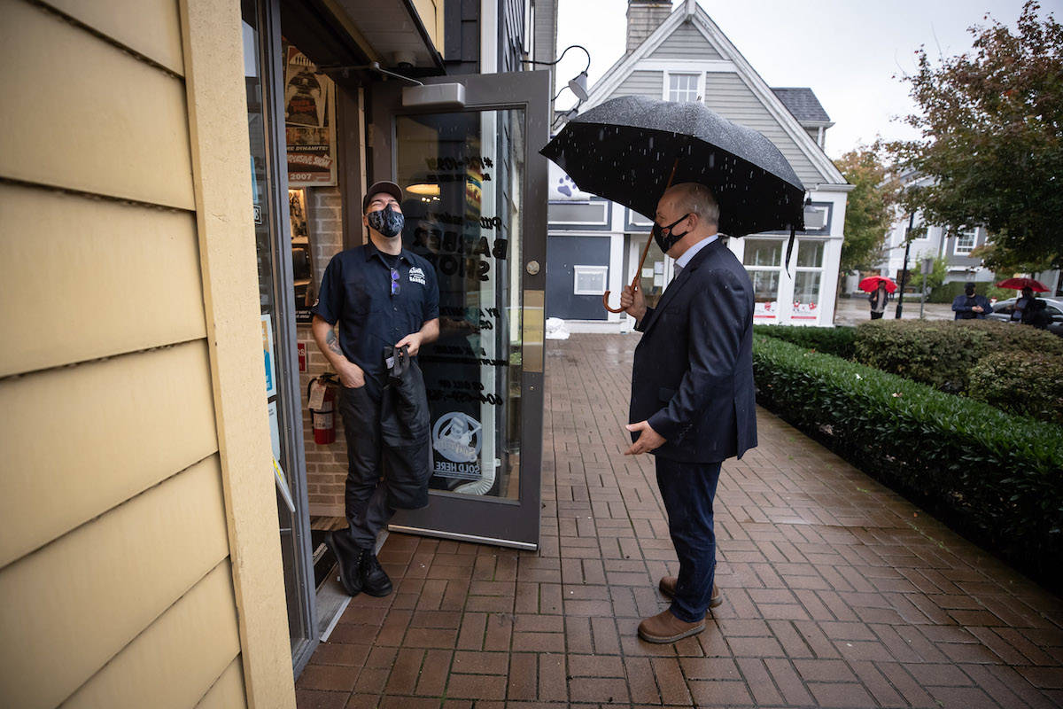 NDP Leader John Horgan speaks with the owner of a barber shop while campaigning in Pitt Meadows, B.C., on Friday, Oct. 16, 2020. Campaigning was restricted by the coronavirus pandemic. THE CANADIAN PRESS/Darryl Dyck