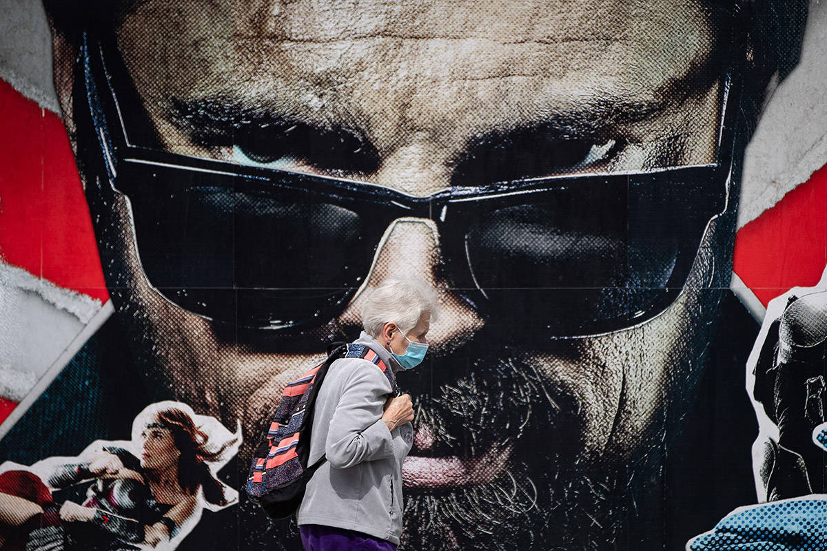 An elderly woman wearing a face mask to curb the spread of COVID-19 walks past an advertisement for a television series in Vancouver, B.C., Sunday, Aug. 30, 2020. THE CANADIAN PRESS/Darryl Dyck