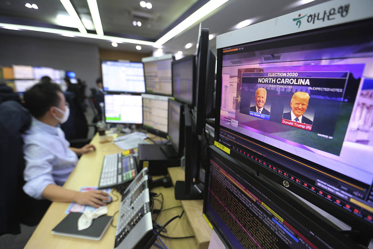 A screen shows a live broadcasting of a news program on the U.S. elections as a currency trader works at the foreign exchange dealing room of the KEB Hana Bank headquarters in Seoul, South Korea, Wednesday, Nov. 4, 2020. (AP Photo/Ahn Young-joon)