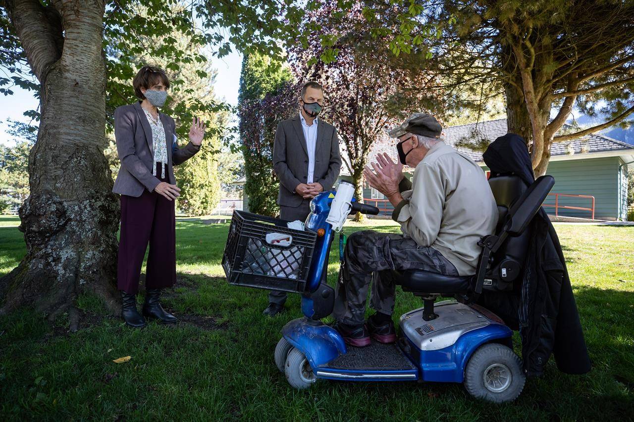 Green Party Leader Sonia Furstenau, left, and local candidate Jeremy Valeriote, second left, listen to Jules Anderson, who said he was living in a homeless shelter, after a campaign stop in Squamish, B.C., on Tuesday, September 29, 2020. A judicial recount is coming for a race in the British Columbia election after mail-in ballots put the Liberals ahead by only 41 votes, in an upset to the Greens. THE CANADIAN PRESS/Darryl Dyck
