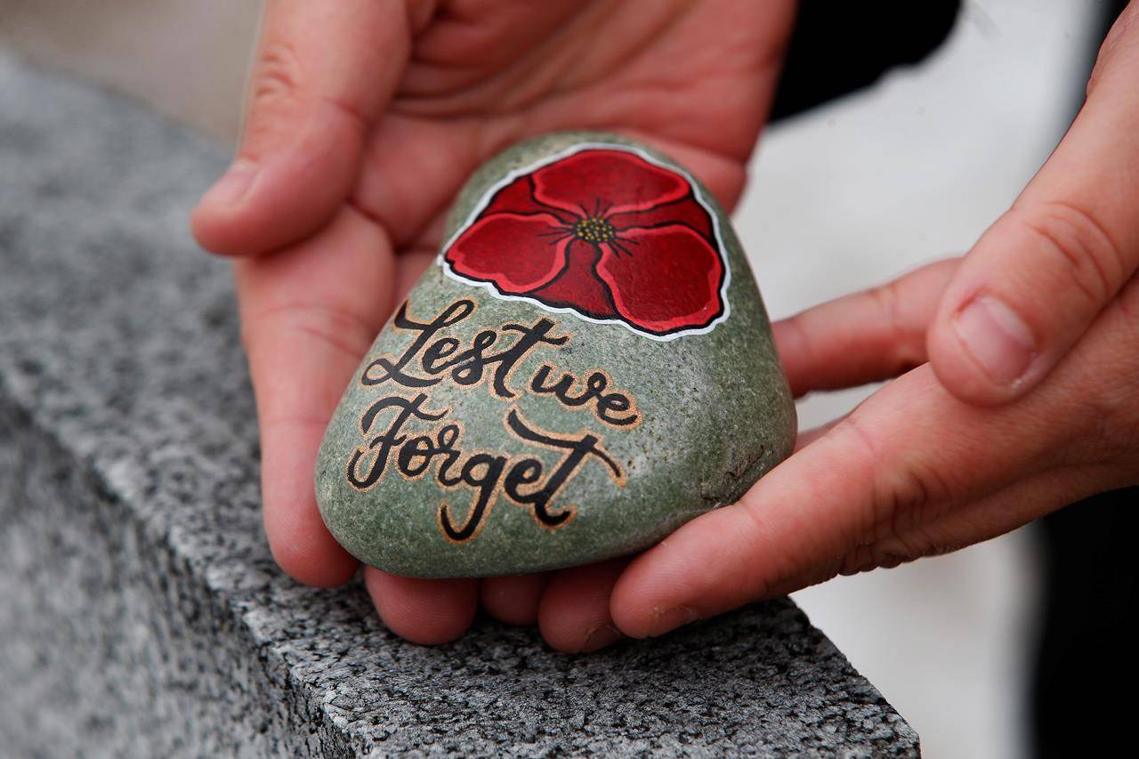 Julie Mungall places her painted stones at the Brookside veterans cemetery in Winnipeg, Saturday, October 24, 2020. Mungall is commemorating Remembrance Day by painting poppies and other designs on rocks and hiding them around the city, sometimes in plain sight, for people to pick up and take home with them. THE CANADIAN PRESS/John Woods