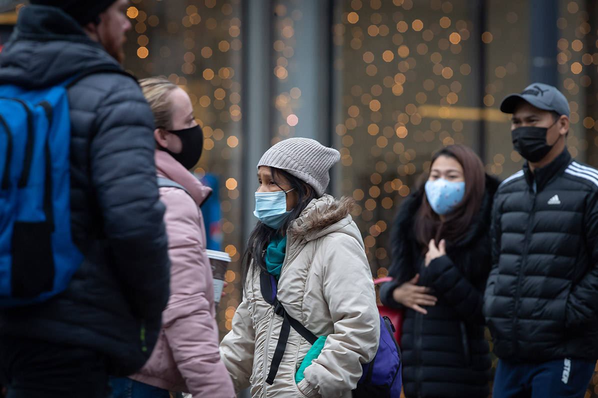 People wearing face masks to help curb the spread of COVID-19 cross a street in downtown Vancouver, on Sunday, November 22, 2020. The use of masks is mandatory in indoor public and retail spaces in the province. THE CANADIAN PRESS/Darryl Dyck
