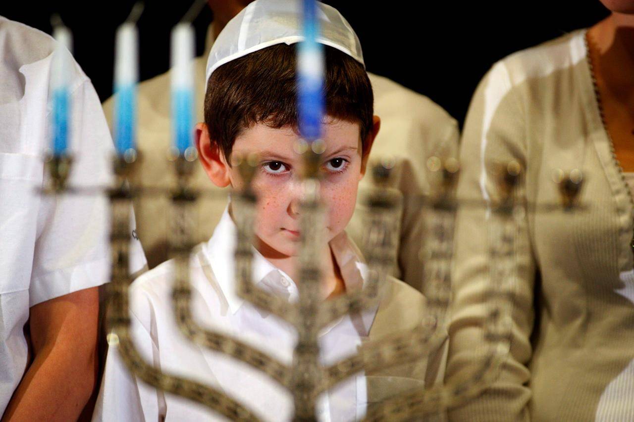 A young boy looks through the menorah during a lighting ceremony at the Calgary Jewish Community Centre on Thursday, Dec. 22, 2011. COVID-19 is prompting Jews to find creative ways to safely celebrate Hanukkah this year. THE CANADIAN PRESS/Jeff McIntosh