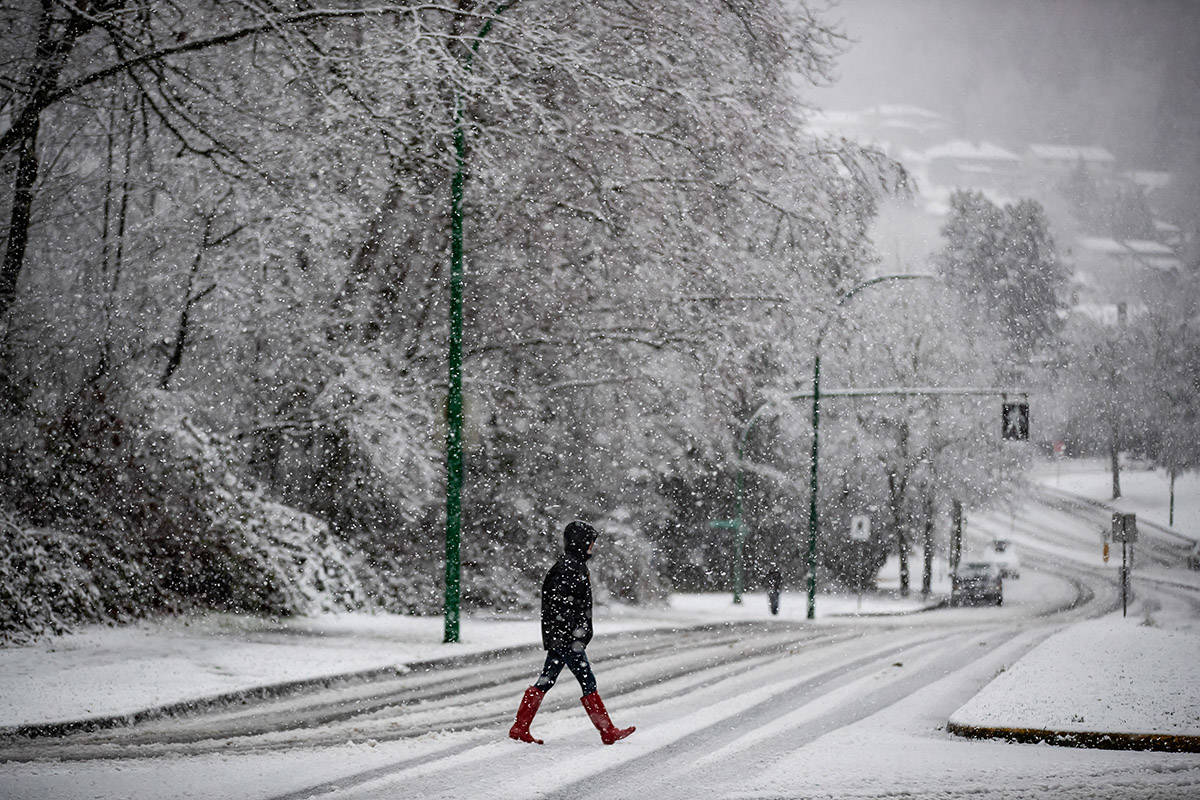 Heavy snow falls as a person crosses a road in Burnaby, B.C., on Monday, December 21, 2020. Environment Canada issued a snowfall warning on the first day of winter with up to 5cm of snow expected for Metro Vancouver and up to 20cm for other areas of the province. THE CANADIAN PRESS/Darryl Dyck