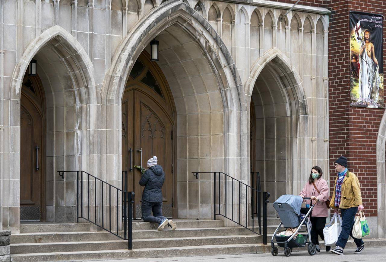 A woman prays on the steps outside St. Casimir Church in Toronto on Friday, May 1, 2020. THE CANADIAN PRESS/Frank Gunn