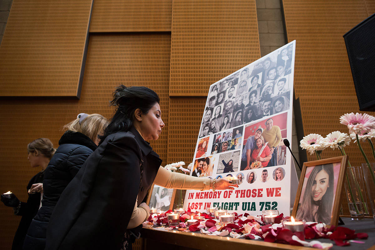 A woman places a candle beneath photographs of some of the people who died in the downing of Ukrainian Airlines Flight 752 in Iran, during a vigil for the victims of the flight, at the Har El synagogue in West Vancouver, on Sunday January 19, 2020. THE CANADIAN PRESS/Darryl Dyck