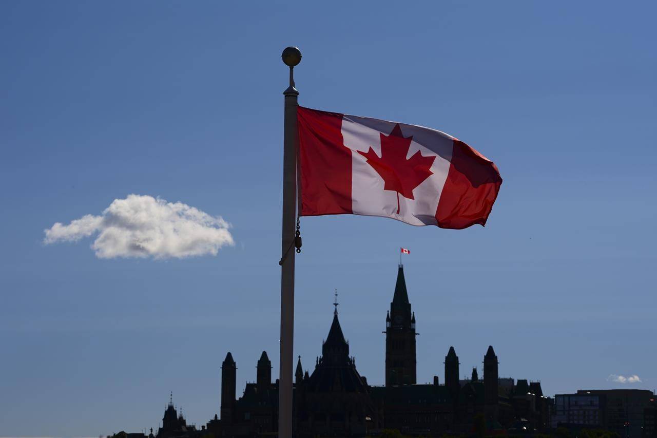 Parliament Hill is viewed below a Canada flag in Gatineau, Quebec, Friday, Sept. 18, 2020. A new poll suggests most Canadians are feeling more grateful for what they have in 2020 as a result of COVID-19 pandemic.THE CANADIAN PRESS/Sean Kilpatrick