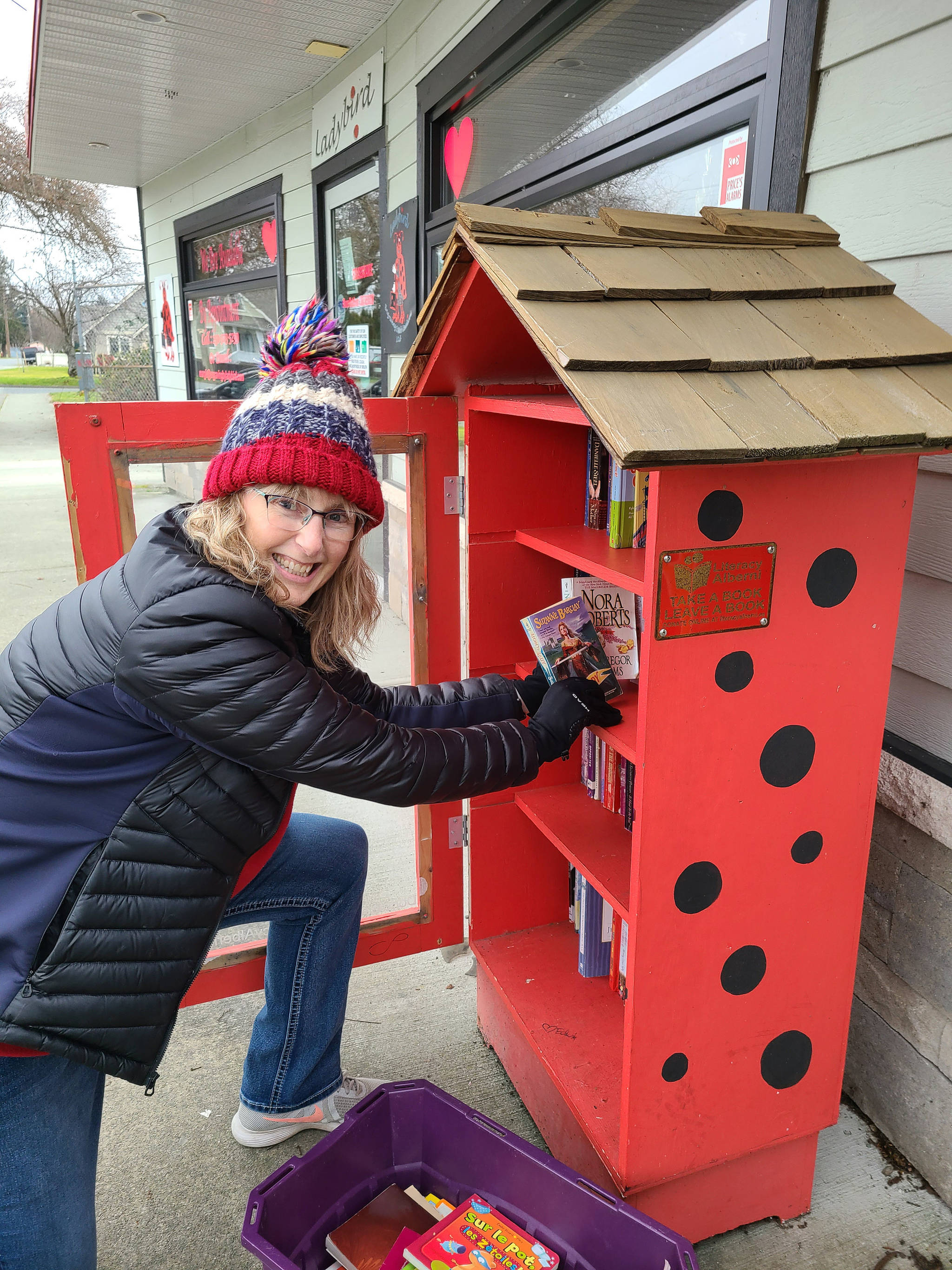 Crystal Knudsen, president of Rotary Club of Port Alberni, restocks the little library in front of Ladybird Engraving on Margaret Street. <ins>The Rotary club is working with Literacy Alberni to revive the libraries.</ins> (SUBMITTED PHOTO)