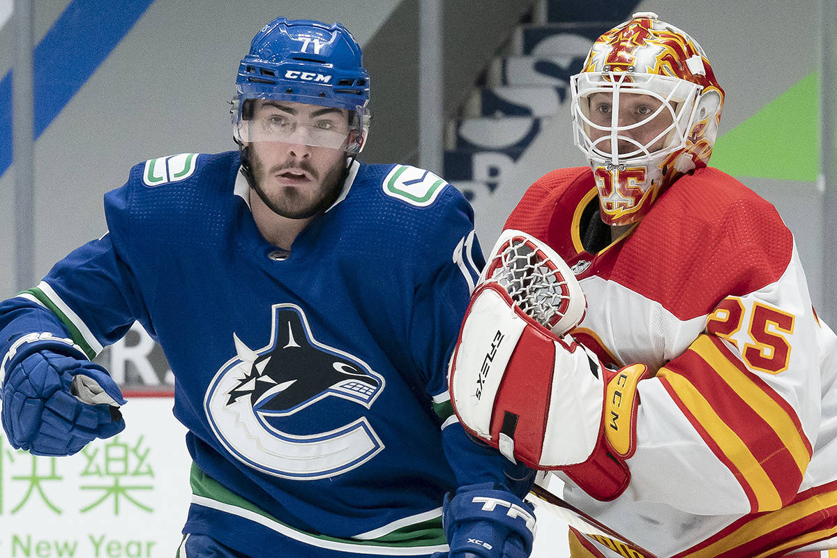Calgary Flames goaltender Jacob Markstrom (25) tires to clear Vancouver Canucks centre Zack MacEwen (71) from in front of the net during second period NHL action in Vancouver, Thursday, Feb. 11, 2021. THE CANADIAN PRESS/Jonathan Hayward