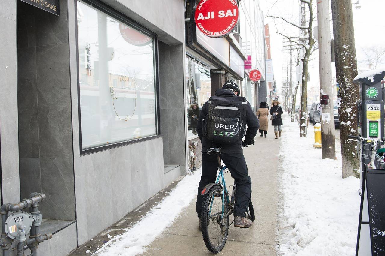 An Uber Eats courier is pictured as they pick up an order for delivery from a restaurant in Toronto on February 27, 2020. THE CANADIAN PRESS/Nathan Denette