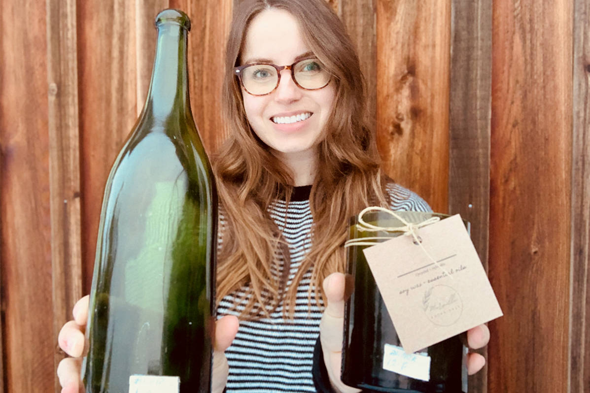Emma Laliberte displays a bottle from the collection and one of her candles. Photo supplied