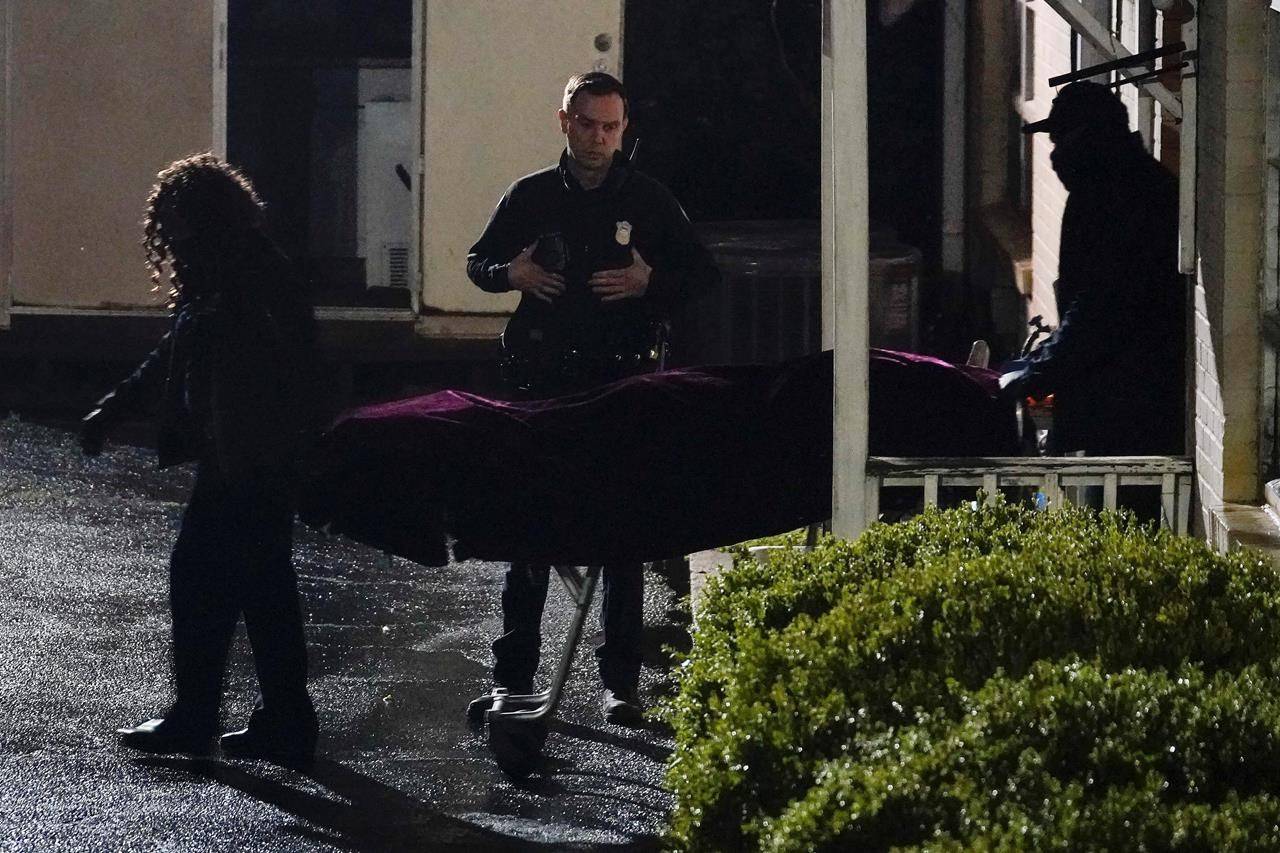 A police officer watches as a body is taken from the Gold Spa massage parlor after a shooting, late Tuesday, March 16, 2021, in Atlanta. Shootings at two massage parlors in Atlanta and one in the suburbs left multiple people dead, many of them women of Asian descent, authorities said. (AP Photo/Brynn Anderson)