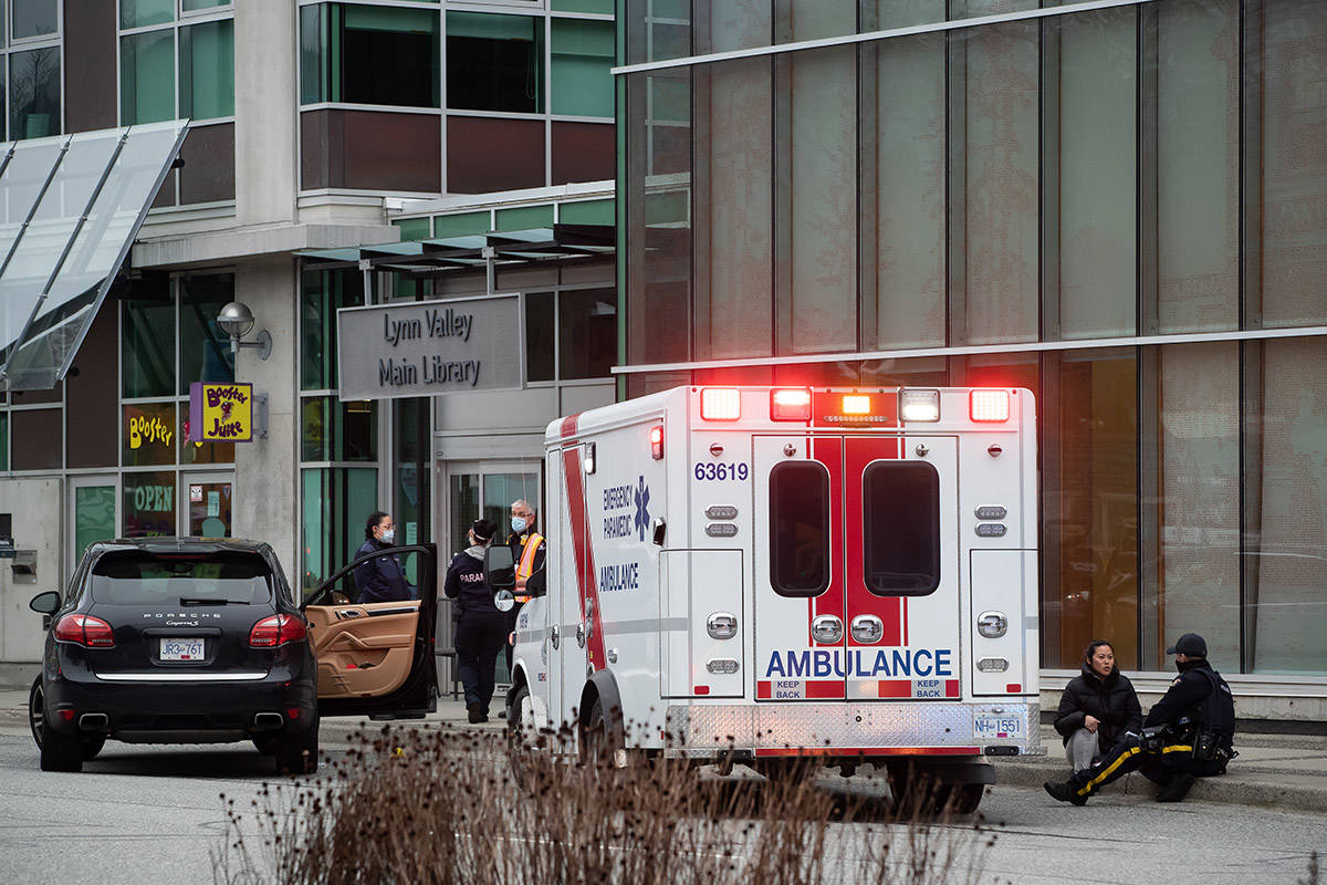 An RCMP officer speaks with a woman while sitting on the curb outside the Lynn Valley Library, in North Vancouver, B.C., Saturday, March 27, 2021. Police say multiple victims were stabbed inside and outside the library today. THE CANADIAN PRESS/Darryl Dyck