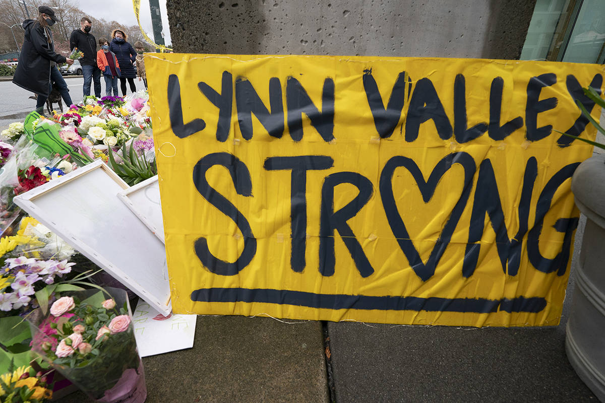 People lay flowers at a makeshift memorial outside of the Lynn Valley Library in Lynn Valley in North Vancouver, B.C., Sunday, March 28, 2021. A 28-year-old man was charged Sunday with second-degree murder in a stabbing rampage that left a young woman dead and injured six others in and around a library in North Vancouver, B.C., a day earlier. THE CANADIAN PRESS/Jonathan Hayward