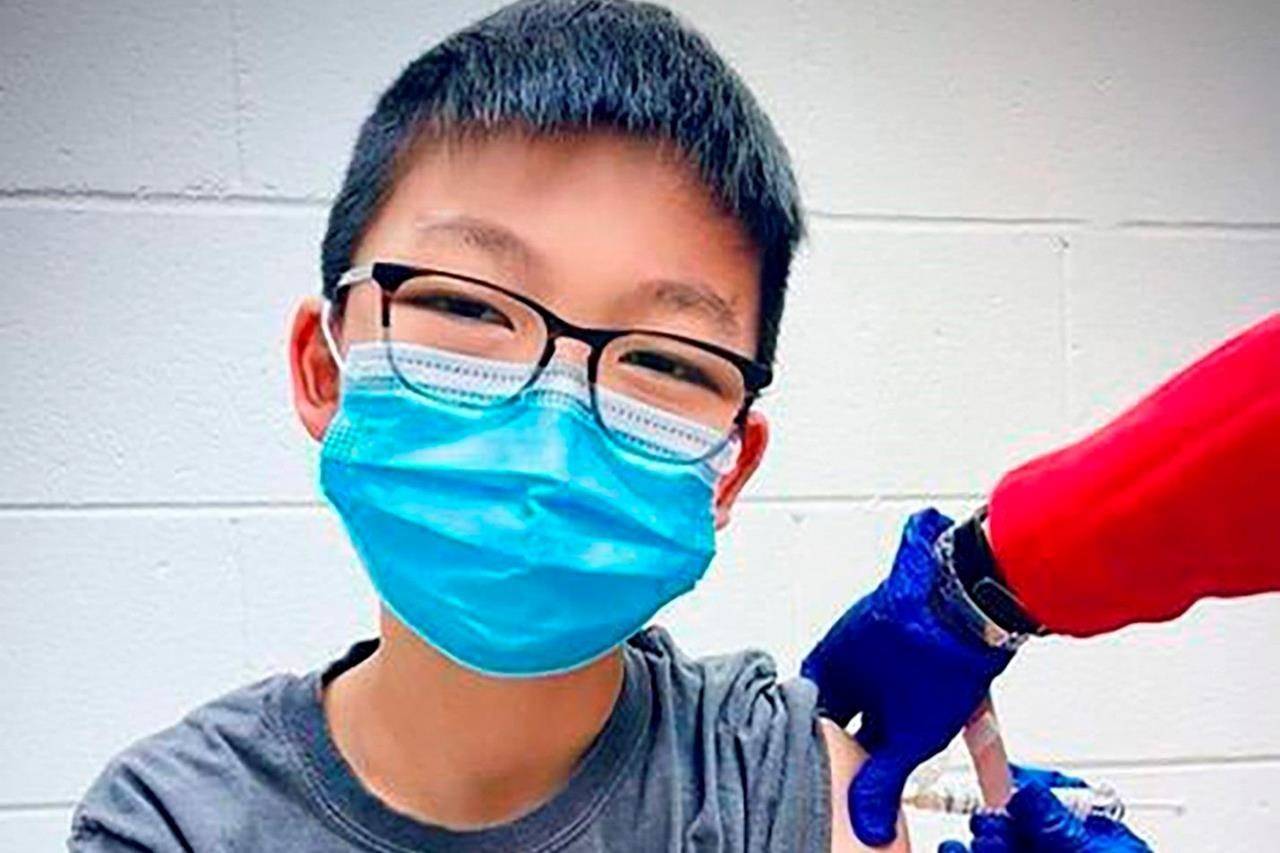 In this Dec. 22, 2020, photo, provided by Richard Chung, his son Caleb Chung receives the first dose of Pfizer coronavirus vaccine or placebo as a trial participant for kids ages 12-15, at Duke University Health System in Durham, N.C. Pfizer says its COVID-19 vaccine is safe and strongly protective in kids as young as 12. The announcement Wednesday, March 31, 2021 marks a step toward possibly beginning shots in this age group before the next school year. (Richard Chung via AP)