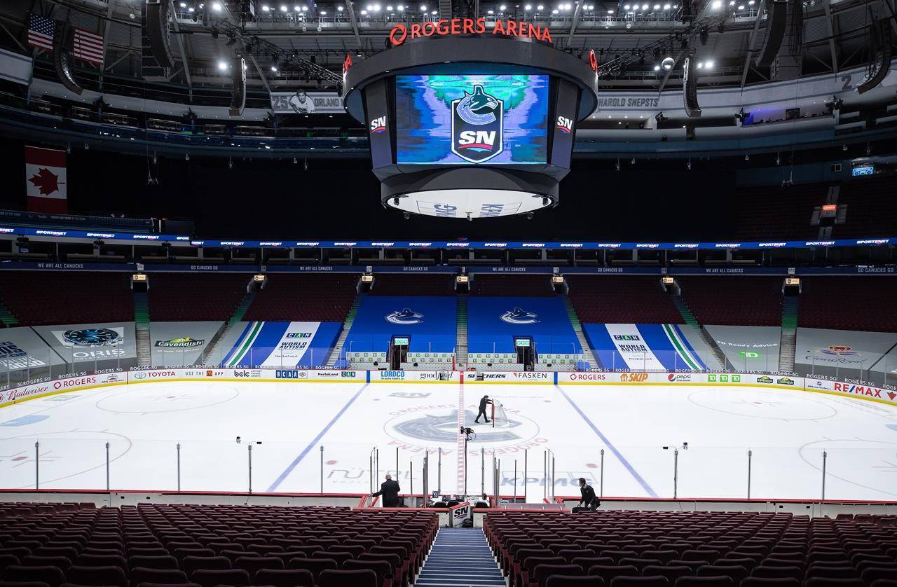 An arena worker removes the net from the ice after the Vancouver Canucks and Calgary Flames NHL hockey game was postponed due to a positive COVID-19 test result, in Vancouver, on Wednesday, March 31, 2021. THE CANADIAN PRESS/Darryl Dyck