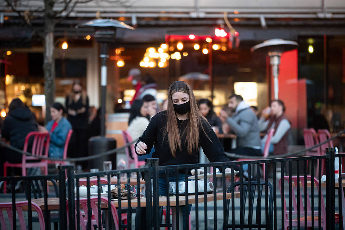 A server clears a table on a patio at a restaurant, in Vancouver, on Friday, April 2, 2021. B.C. has banned indoor dining at restaurants and bars as part of a three-week measure to curb the spread of COVID-19 amid growing concern about the spread of COVID-19 variants. THE CANADIAN PRESS/Darryl Dyck