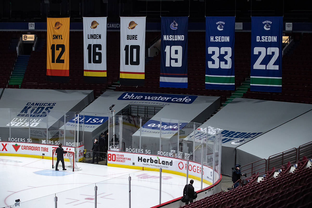 An arena worker removes the net from the ice after the Vancouver Canucks and Calgary Flames NHL hockey game was postponed due to a positive COVID-19 test result, in Vancouver, on Wednesday, March 31, 2021. THE CANADIAN PRESS/Darryl Dyck