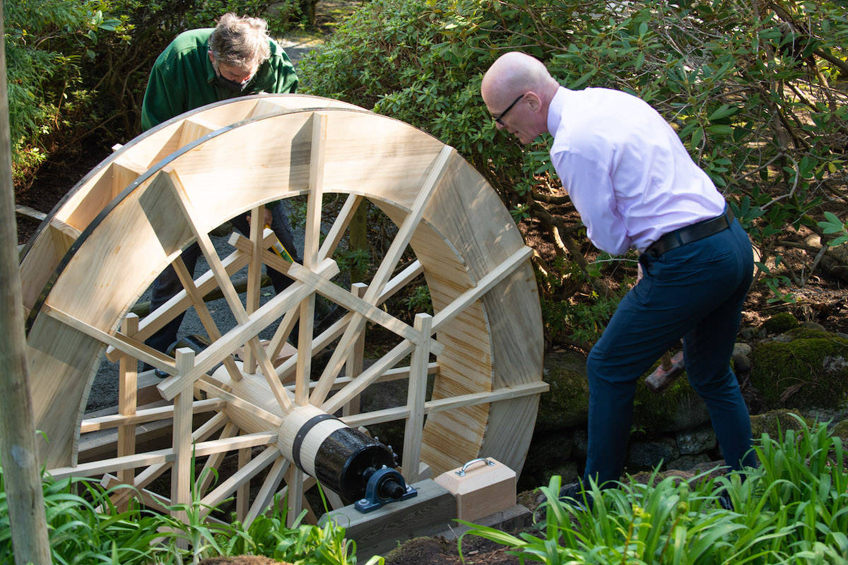 Royal Roads University president Philip Steenkamp and gardener Greg Higgs restart the restored water wheel at the campus’ Japanese Garden. (Photo courtesy of Royal Roads University)