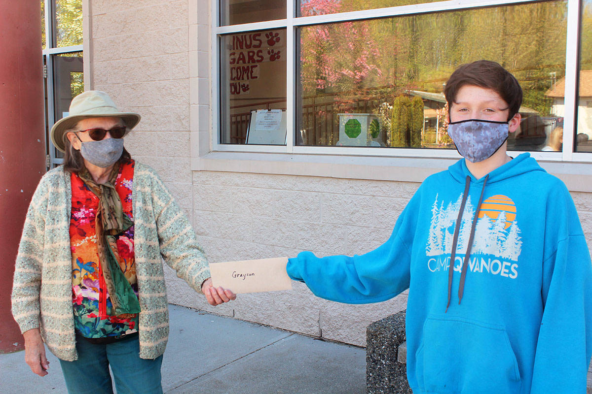 Nancy Bright presents an envelope to Grayson Magee containing $50 in appreciation for helping her after a fall in Askew Creek in Chemainus. (Photo by Don Bodger)