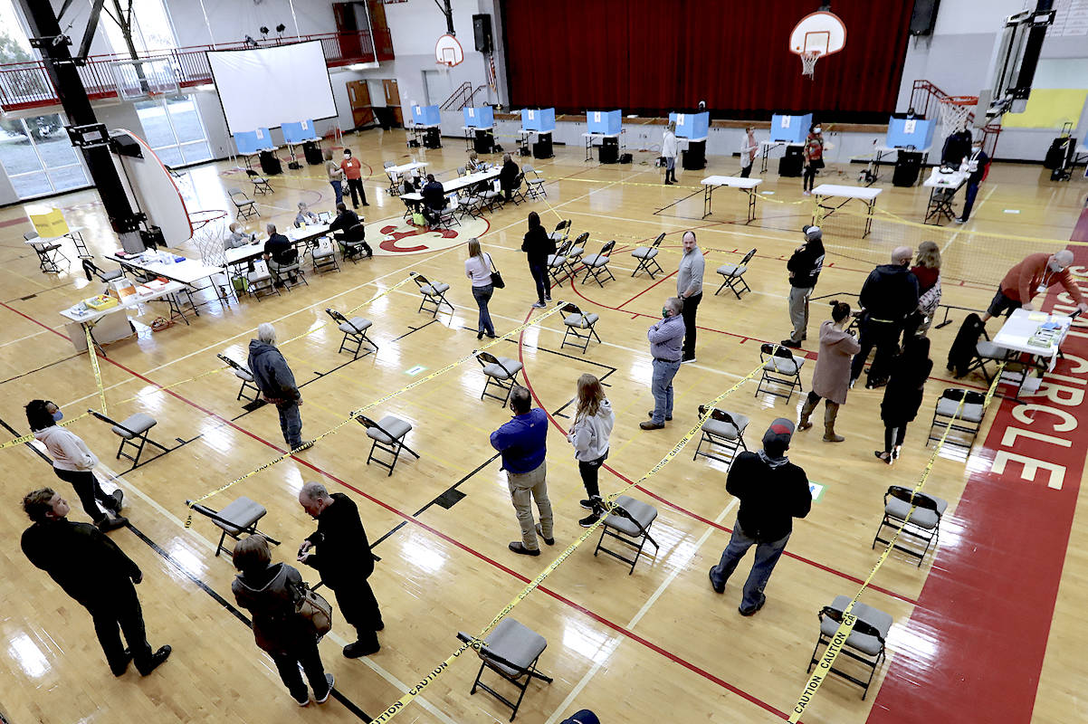 Voters socially distance while waiting in line. (Curtis Compton/AP)