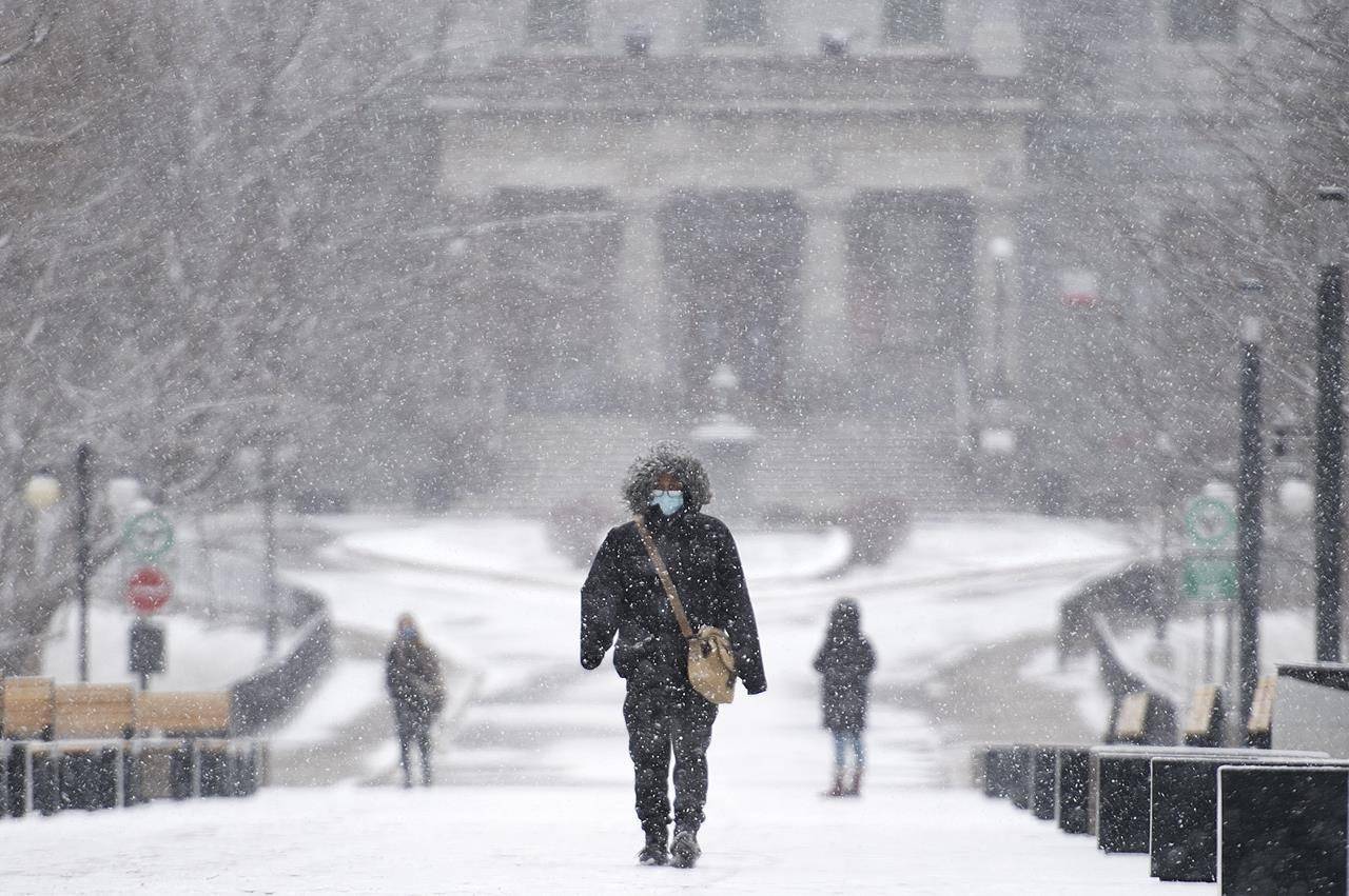 A person wears a face mask as they walk through McGill University during light snowfall in Montreal, Sunday, December 20, 2020 as the COVID-19 pandemic continues in Canada and around the world. THE CANADIAN PRESS/Graham Hughes