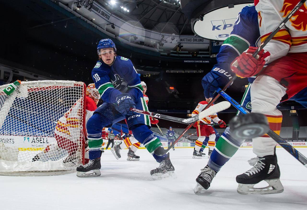 Vancouver Canucks’ Jake Virtanen (18) and Calgary Flames’ Josh Leivo, front right, vie for the puck as goalie Jacob Markstrom, back left, watches during the first period of an NHL hockey game in Vancouver, on Saturday, February 13, 2021. THE CANADIAN PRESS/Darryl Dyck