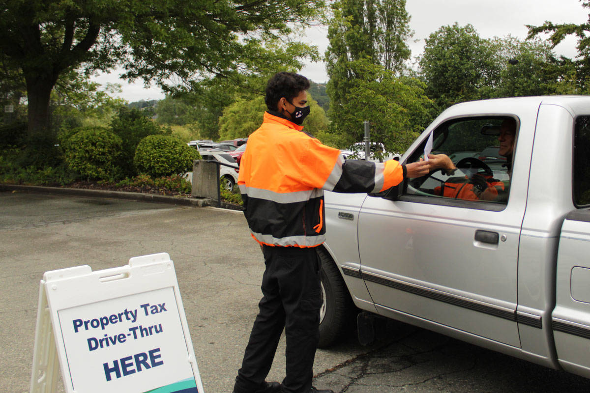Karan Yadav, a security guard with Footprints Security, assisted residents at the property tax drive-thru located outside Saanich municipal hall in 2020. (Black Press Media file photo)