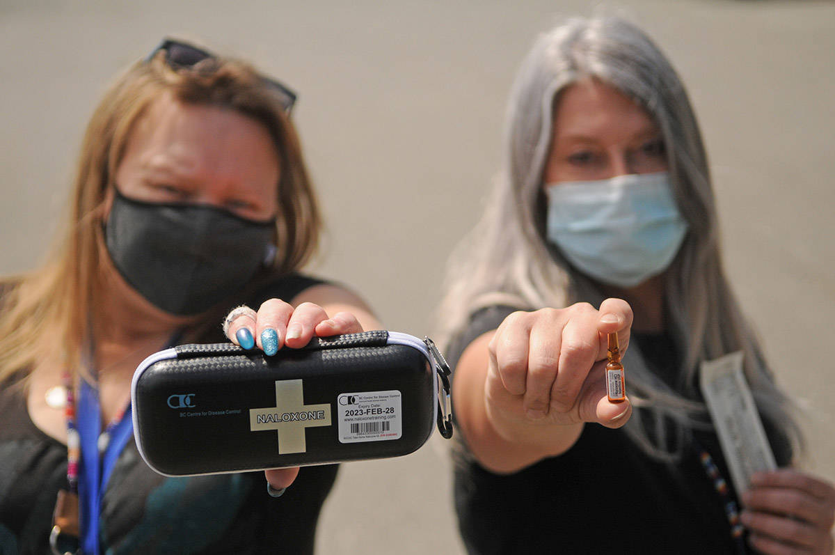 Jodi Higgs (right) holds a vial of naloxone and Christine Christensen holds a kit in the parking lot of the Pacific Community Resources Society in Chilliwack on Thursday, May 20, 2021. The society is offering a number of upcoming events, workshops and videos to help educate friends and family members who have loved ones that are drug users. (Jenna Hauck/ Chilliwack Progress)