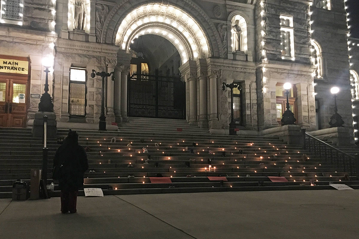 An onlooker stands at the foot of the B.C. legislature steps, where numerous shoes, stuffed animals and candles paid homage to 215 Indigenous children whose remains were found buried at the site of a residential school in Kamloops. (Don Descoteau/News Staff)