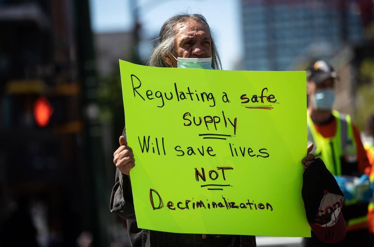 A man holds a sign during a protest against the proposed Vancouver Model for illicit drug decriminalization, in the Downtown Eastside of Vancouver, on May 11, 2021. THE CANADIAN PRESS/Darryl Dyck