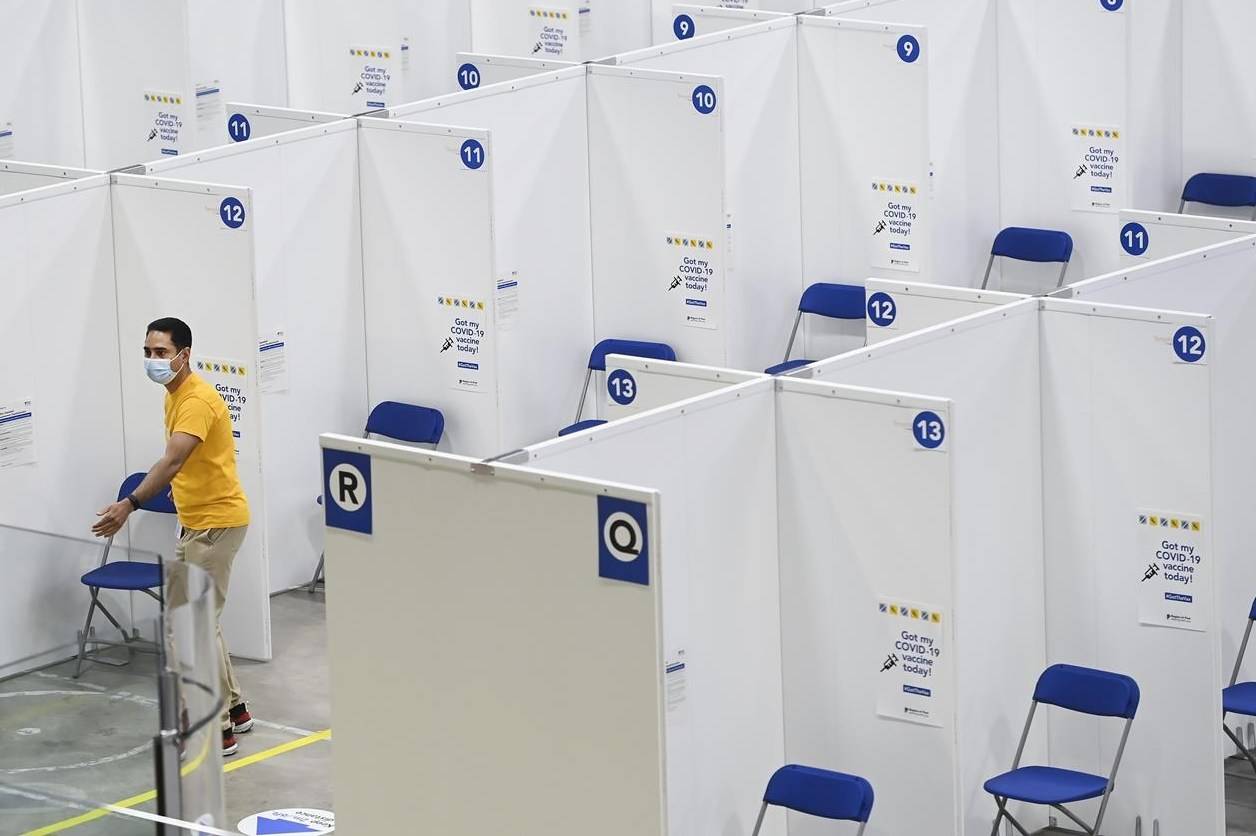 A man walks through rows of chairs and privacy cubicles at the “Hockey Hub” mass vaccination centre, known as the CAA Centre, during the COVID-19 pandemic in Brampton, Ont., on Thursday, June 3, 2021. This NHL-sized hockey rink is one of Canada’s largest vaccination centres. THE CANADIAN PRESS/Nathan Denette