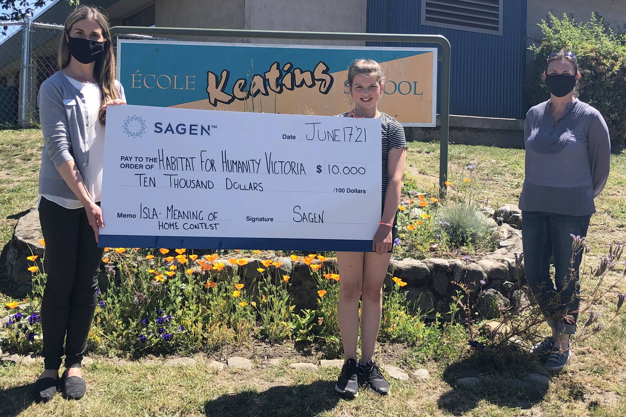 Kelly King with Habitat for Humanity Victoria, accepts a representative cheque for $10,000 from Isla Verhagen, a Grade 4 student at Keating Elementary, while Kathryn Parfitt with founding sponsor Sagen looks on. Verhagen earned the prize with her entry in the Meaning of Home writing contest, the only one written in French. (Courtesy of Habitat for Humanity Victoria)