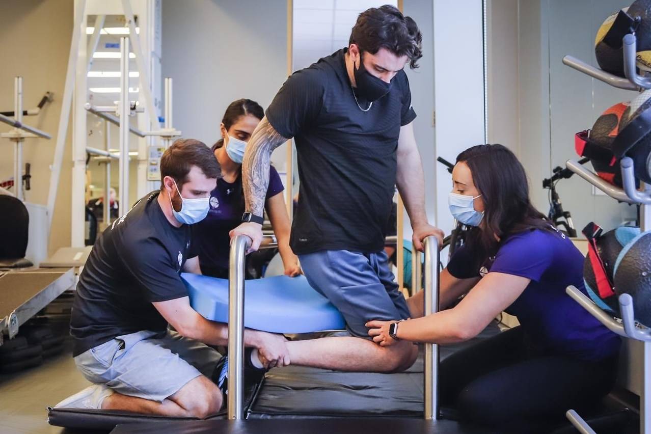 Humboldt Broncos bus crash survivor Ryan Straschnitzki, centre, is helped to turn his body by Eric Daigle, left, and Jill Mack while he attends a physiotherapy session in Calgary on Thursday, June 24, 2021. THE CANADIAN PRESS/Jeff McIntosh
