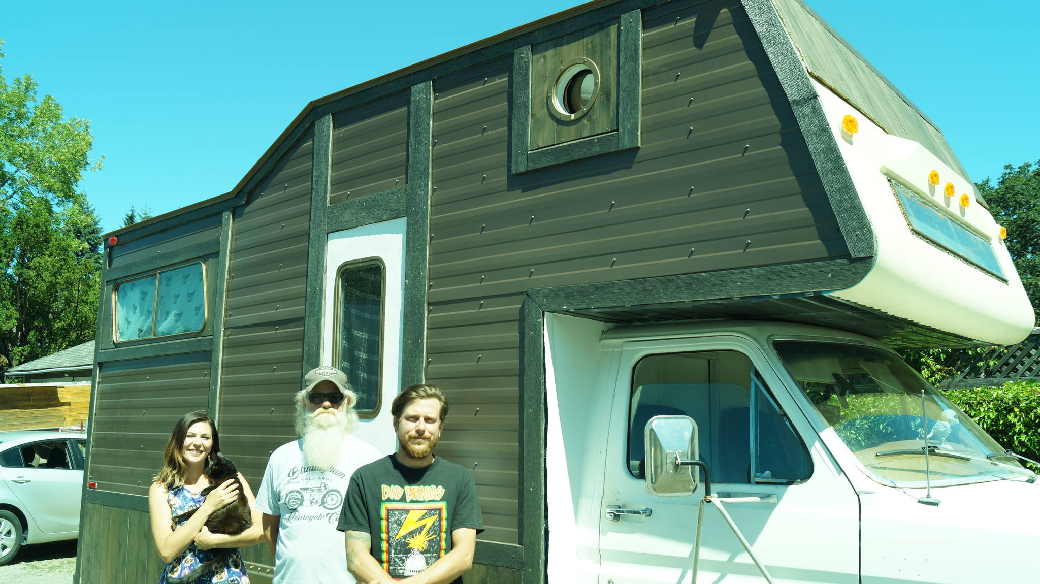 Catherine Richard, with Penelope their cat, Mark Peterson and Chris Laxton alongside the RV the couple rebuilt, with some neighbourly assistance from Peterson and the community. (Rick Stiebel/News Staff)