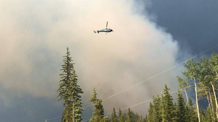 Firefighters assess a fire over Watch Lake Road Wednesday evening. (Patrick Davies photo - 100 Mile Free Press)