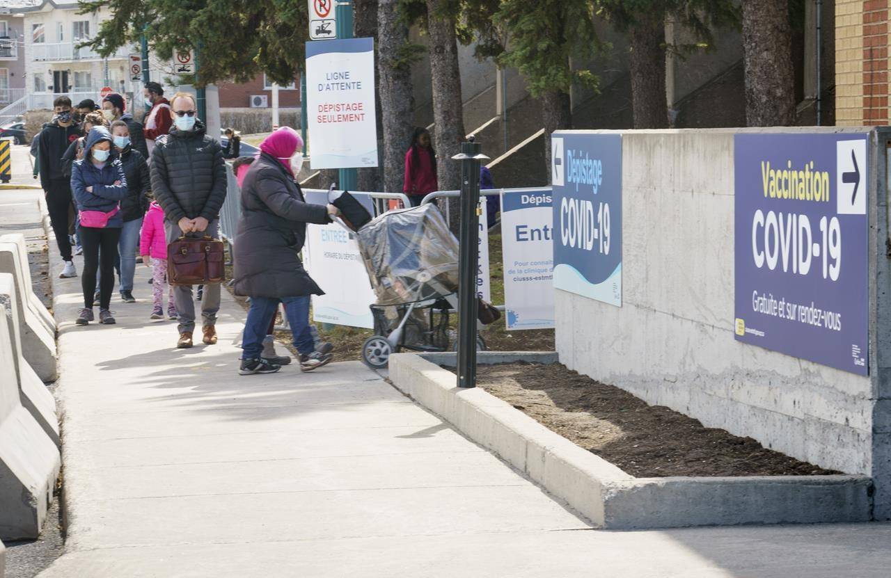 People wait in line to enter a COVID-19 test clinic next to a COVID-19 vaccination clinic in Montreal, on Wednesday, April 7, 2021. THE CANADIAN PRESS/Paul Chiasson