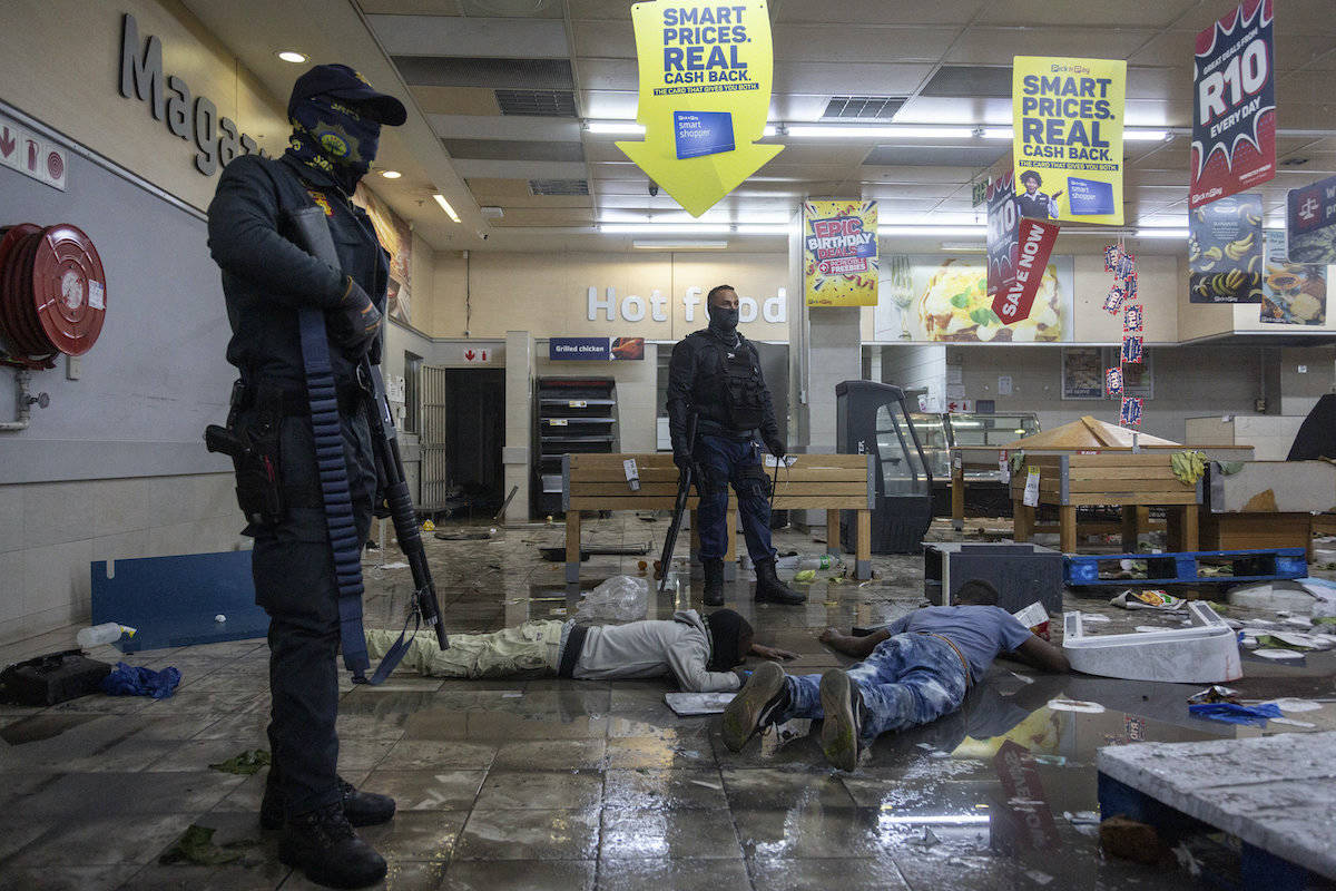 Police stand over arrested suspect looters in a shopping centre in Alexandra township, Johannesburg, South Africa, Monday, July 12, 2021. Police say six people are dead and more than 200 have been arrested amid escalating violence during rioting that broke out following the imprisonment of South Africa’s former President Jacob Zuma. (AP Photo/Yeshiel Panchia)