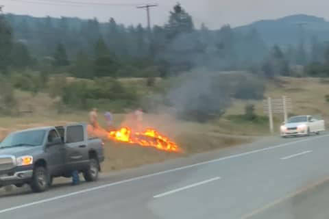 Two Okanagan Restoration Service employees snuffed a small blaze burning along Highway 97A in Spallumcheen Monday, July 12, 2021. (Okanagan Restoration Services Ltd. - Facebook)