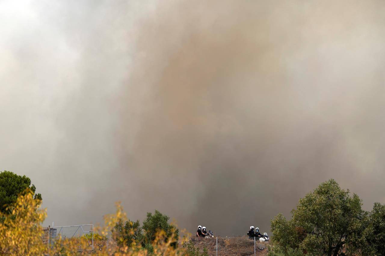 Police patrol during a wildfire in Agios Konstantinos village about 60 kilometers (37 miles) south of Athens, Greece, Monday, Aug. 16, 2021. Greek authorities have deployed dozens of firefighters, as well as six water-dropping planes and four aircraft to a wildfire that broke out Monday morning in the Keratea region southeast of Athens, near the national park of Sounion. (AP Photo/Thanassis Stavrakis)