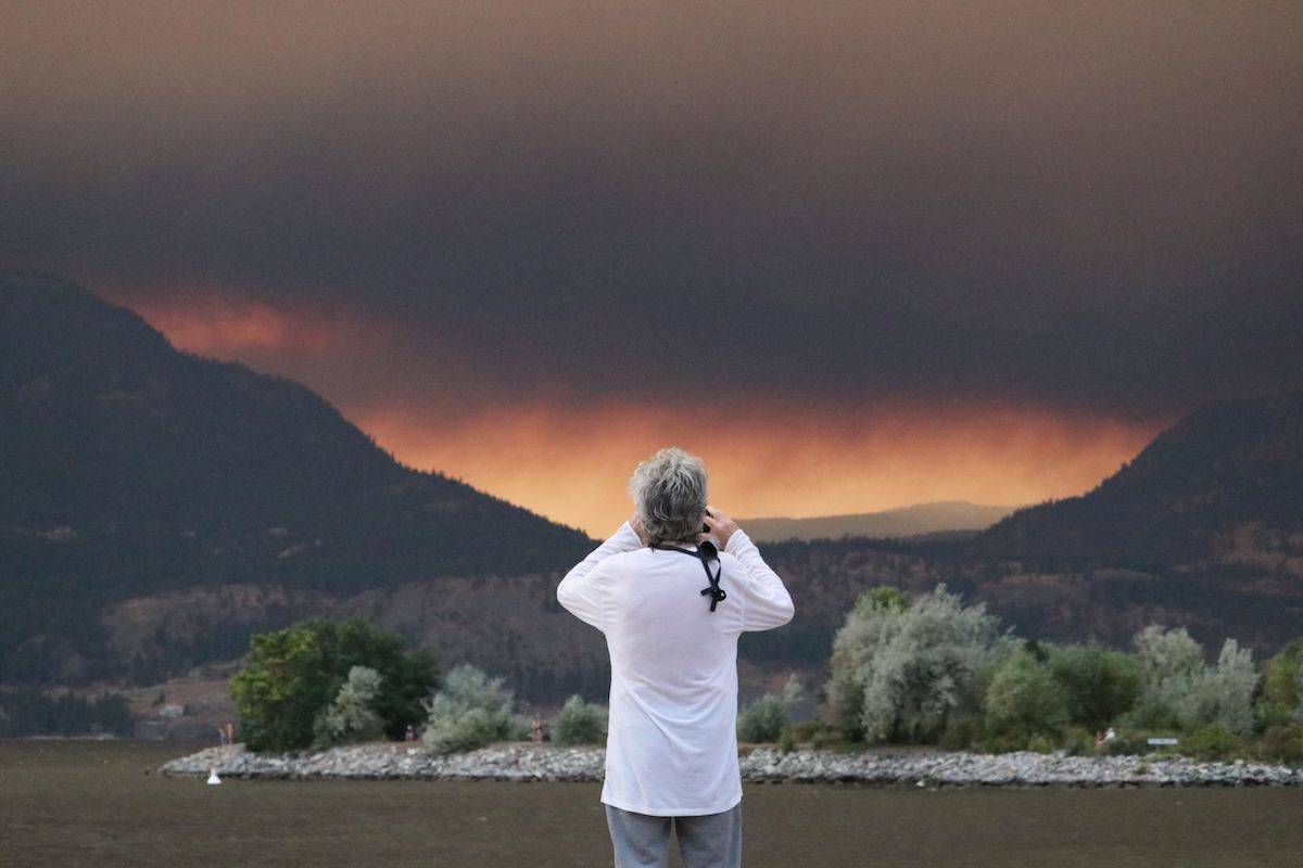 A man looks towards the White Rock Lake fire from downtown Kelowna on Aug. 15, 2021. (Aaron Hemens/Capital News)