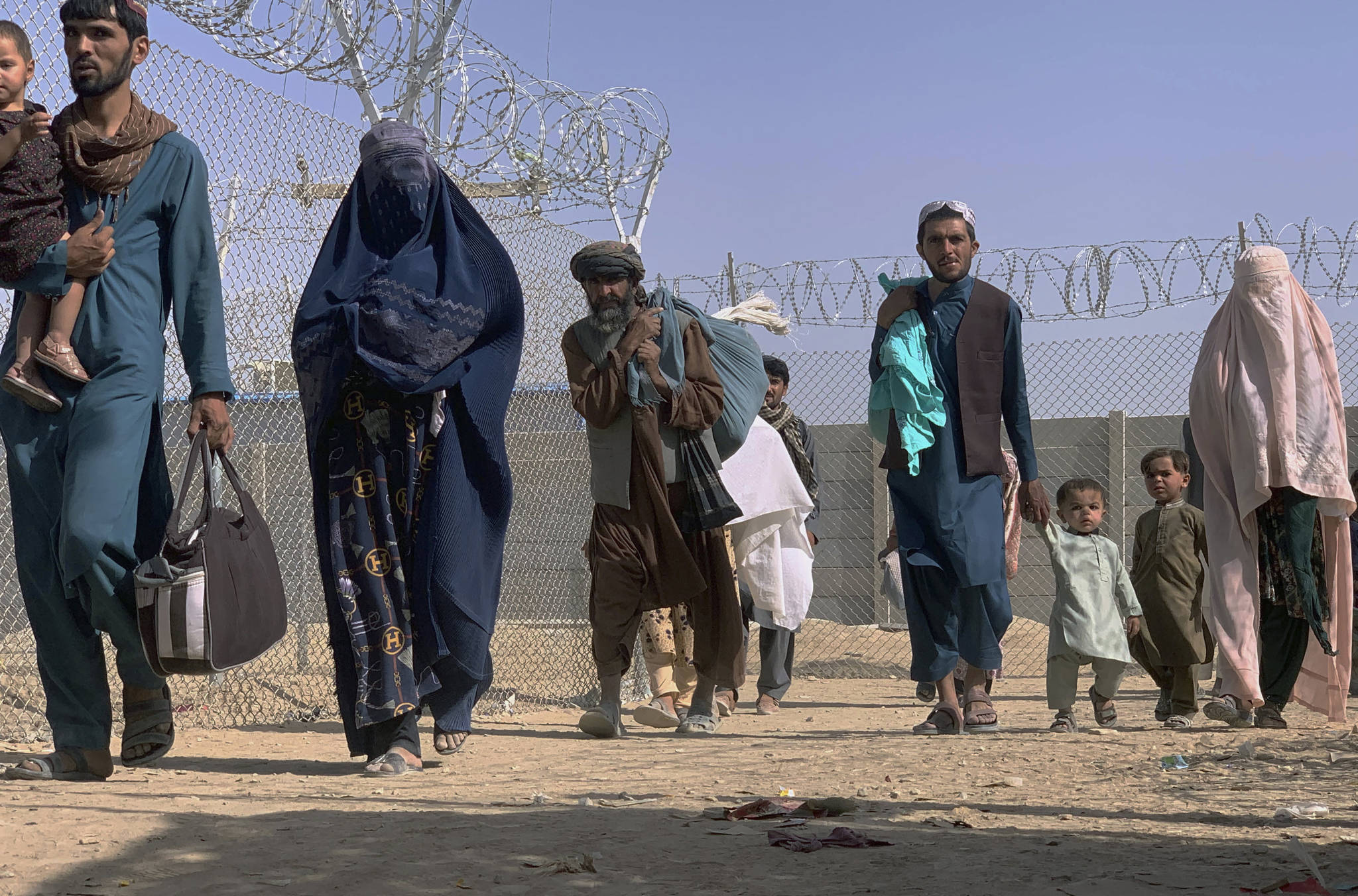 Afghans walk through a security barrier as they enter Pakistan through a common border crossing point in Chaman, Pakistan, Thursday, Aug. 26, 2021. Hundreds of Pakistanis and Afghans cross the border daily through Chaman to visit relatives, receive medical treatment and for business-related activities. Pakistani has not placed any curbs on their movement despite recent evacuations from Kabul. (AP Photo)