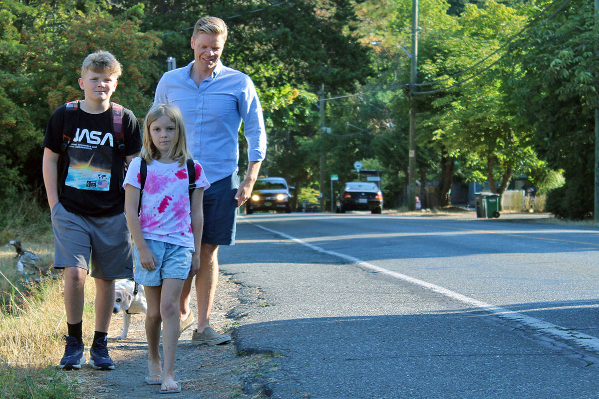 Caelum Murdock (left), Avery Murdock, and Dean Murdock walk on a shoulder of the road in Saanich en route to school. (Megan Atkins-Baker/News Staff)